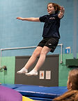 Young gymnast, seat landing on trampoline