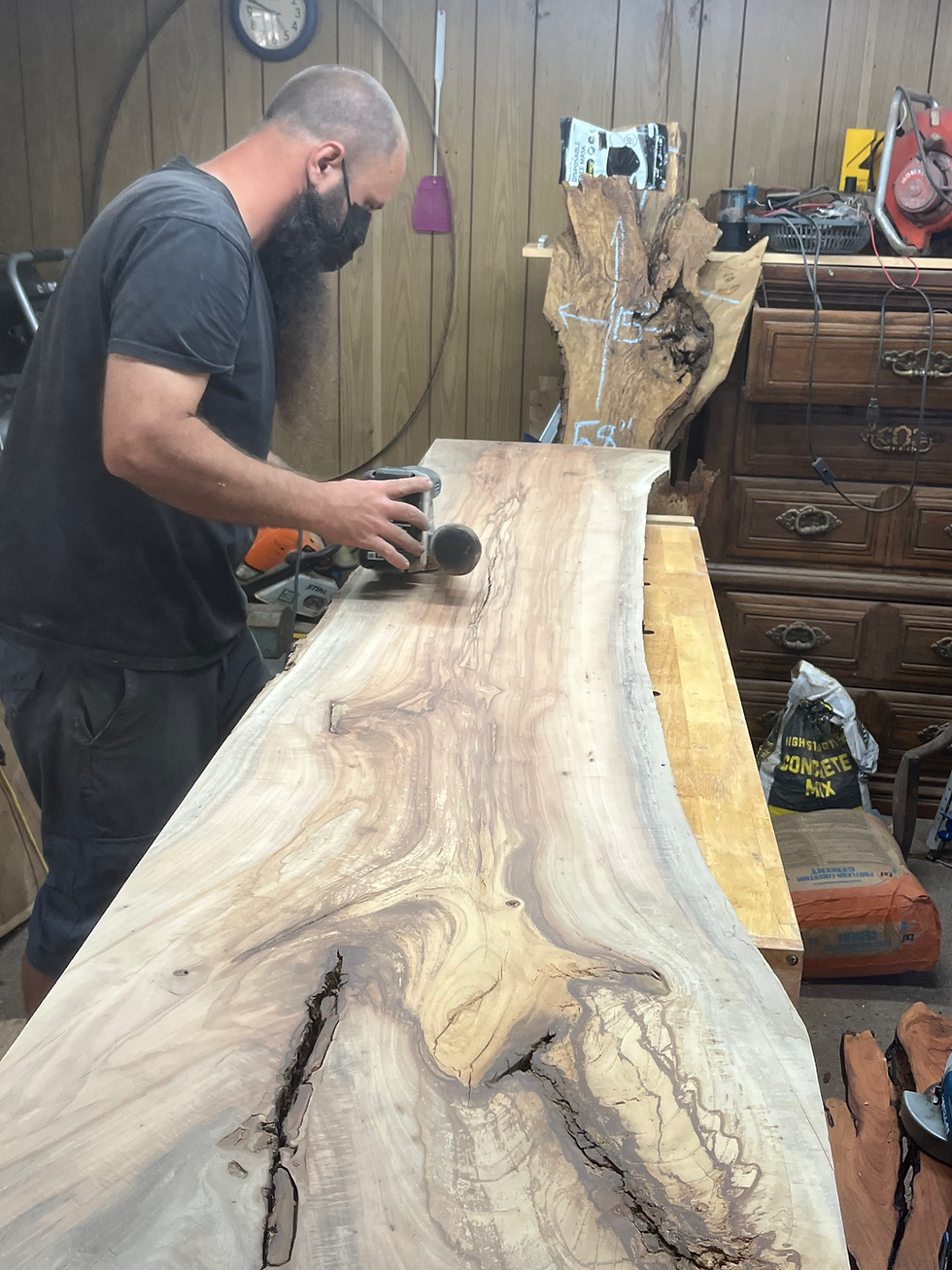 Eye-level view of a live edge slab with sanding tools on a workbench