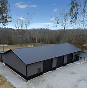 Modern gray building with dark roof in wooded setting