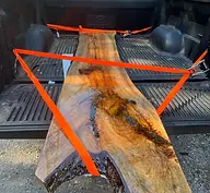 high quality Live-edge wood slab secured with orange straps in truck
