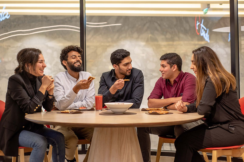 five team members sitting down holding food and laughing while discussion digital marketing in DSO