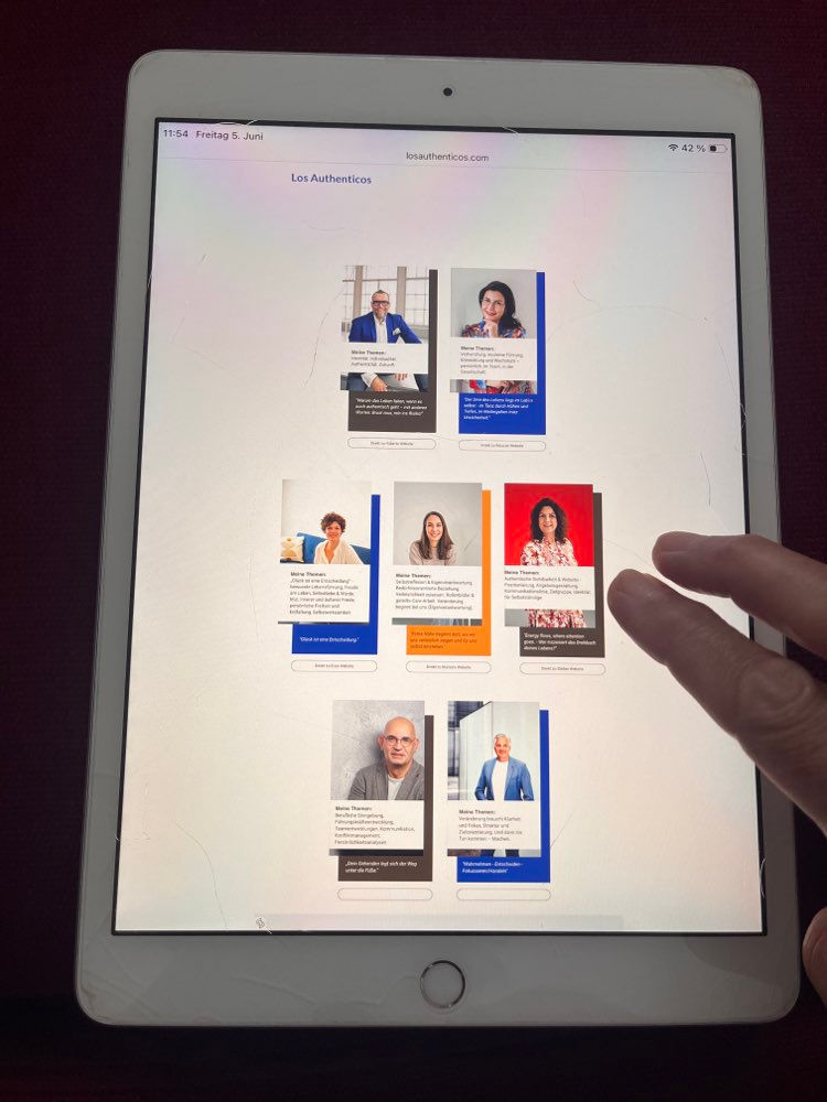 Hand tippt auf iPad mit Los-Authenticos-Seite und Porträtkarten; oben steht losauthenticos.com, helle Oberfläche.