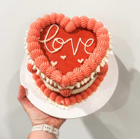 small pink and white heart cake that says love on top