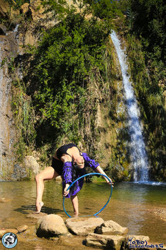 Gymnast with a hoop near a waterfall