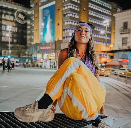 Γυναίκα με κίτρινα παντελόνια κάθεται σε δρόμο τη νύχτα