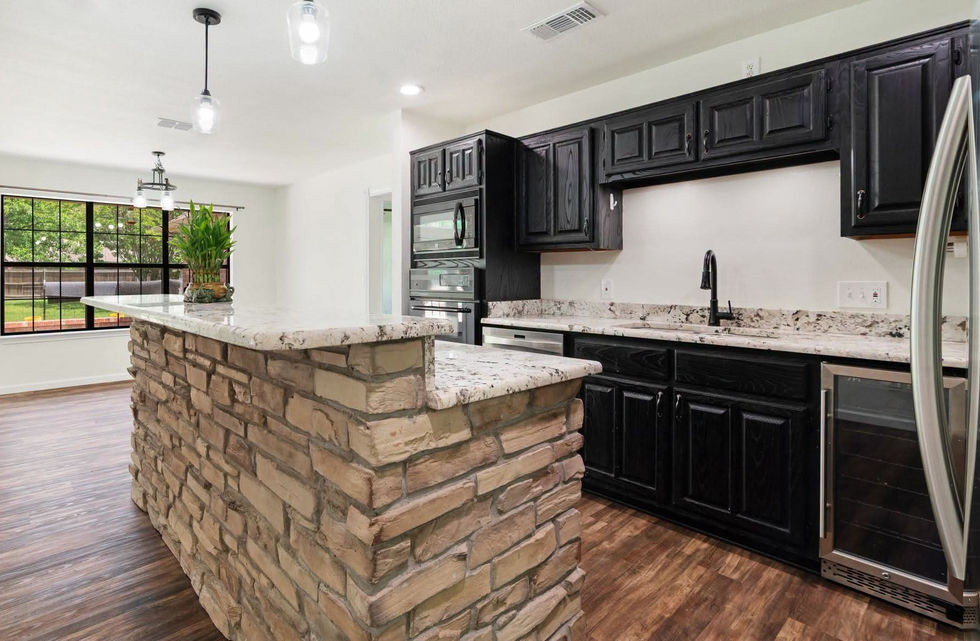 Sideview of kitchen featuring an island with mixed brown Rustic Ledgestone rock and black cabinets.