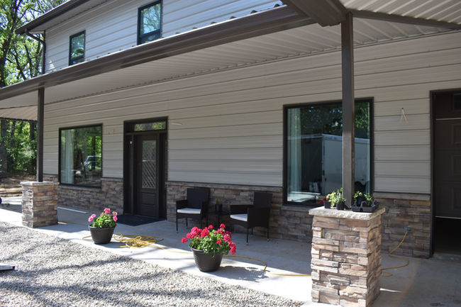 Beige barndominium with Buffalo brown dry stack stone wainscotting. 
