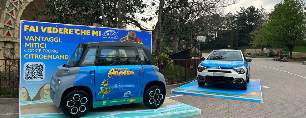 La Citroën AMI, la petite voiture électrique urbaine de Citroën, est présentée sur un panneau aux abords de l'entrée principale de Gardaland en Italie. Cette voiture compacte et facile à conduire est parfaite pour se déplacer en ville et explorer les environs du parc d'attractions