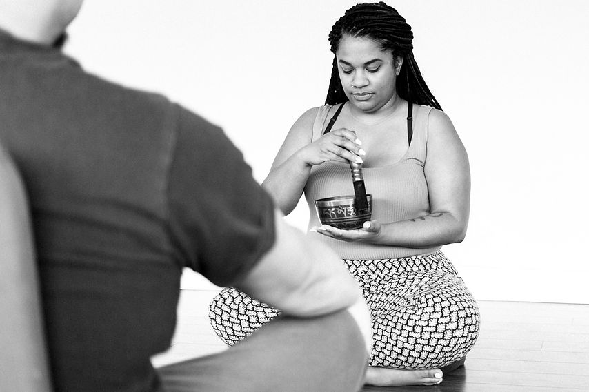 A Black yoga instructor teaching a male student meditation