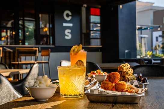 A table filled with cocktails and appetizers at Cross Street Del Mar