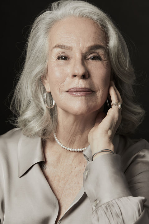 צילום פורטרט ביוטי של אישה מבוגרת מאופרת באיפור לעור בוגר עם שיער כסוף מביטה למצלמה