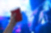 Young man holding red party cup in nightclub dance floor. Alcohol container in hand in dis