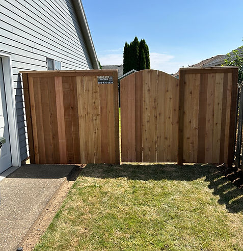 After picture of a side yard that has a privacy cedar fence built with a custom curved top man gate.
