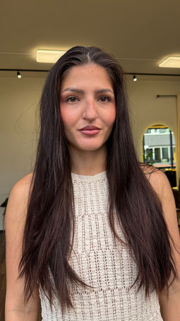 Front view of a woman before her luxury caramel balayage featuring a seamless root melt, soft face-framing highlights and long, glossy hair styled in soft waves at Emberyl Hair Atelier in Zürich.