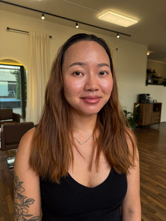 Front and back view of a colour correction from warm copper hair to a seamless blonde balayage with a soft root melt, face-framing highlights and glossy waves at Emberyl Hair Atelier in Zürich.