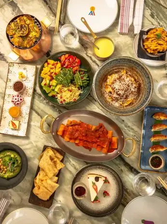 Colorful spread of gourmet dishes—seafood, fusion mains, and elegant desserts—arranged on a stylish table at a trendy Dubai restaurant, with diners enjoying a festive ambience during Restaurant Week 2025.