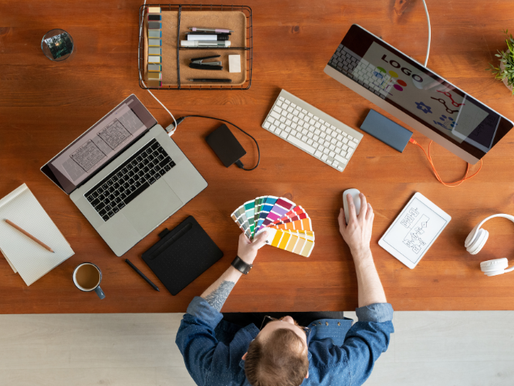 Designer working at a desk with color swatches, logo concepts, and digital tools, representing how a strong brand identity sets you apart from competitors.
