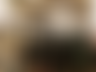 Industrial machine room with green compressors, black pipes, and control panels. The ceiling has bright lights. Overall, a clean, organized setting.