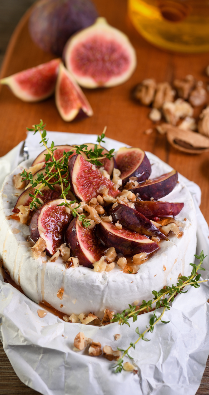 Wheel of baked brie with sliced figs, almonds, and thyme leaves on top