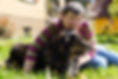 Person sitting on grass hugging their dog. 