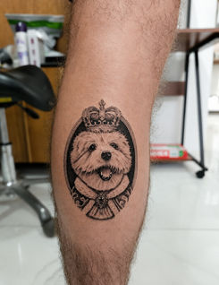 Realism dog portrait tattoo with a crown and decorative frame created at White Sloth Tattoo Studio in Tamarindo, Costa Rica.