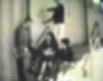 Blind high school boy approaches stairs using two-handed trailing technique. A group of 3 students sits on the steps in his way.