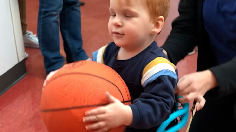 A belted white cane allows a blind child to easily play ball and be aware of his surroundings.