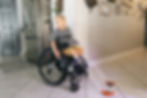 Eye-level view of a boy in a wheelchair wearing a belt cane in his family's kitchen.