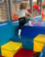 two-year-old girl climbs to top of playscape mountain wearing her belt cane.