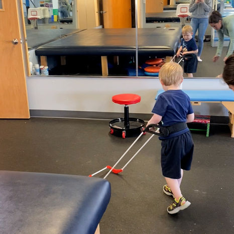 a boy wearing a belt cane walks past a mirror