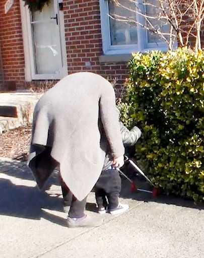 Student M. reaches his hand ahead to locate the bush his cane frame has pushed into.