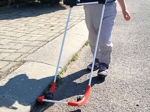 a child walks along a curb wearing his belt cane