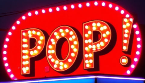 Bright red neon POP! sign with pink bulb border glowing at night