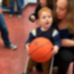 3-year-old boy walks holding a basketball wearing a belt cane as his teacher spots him from behind