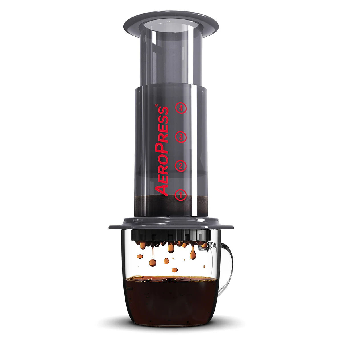 AeroPress brewing coffee with dark droplets falling into a clear glass mug.