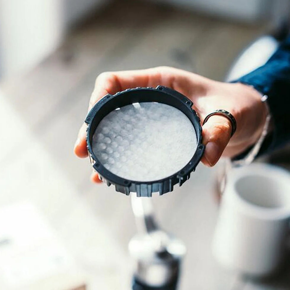 Thumbnail: Hand holding an AeroPress filter cap with a white paper filter inserted.