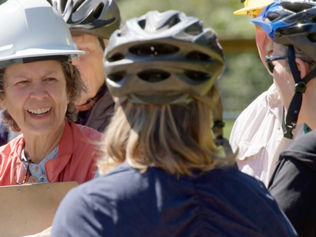 women wearing bike and construction helmets talking in a group