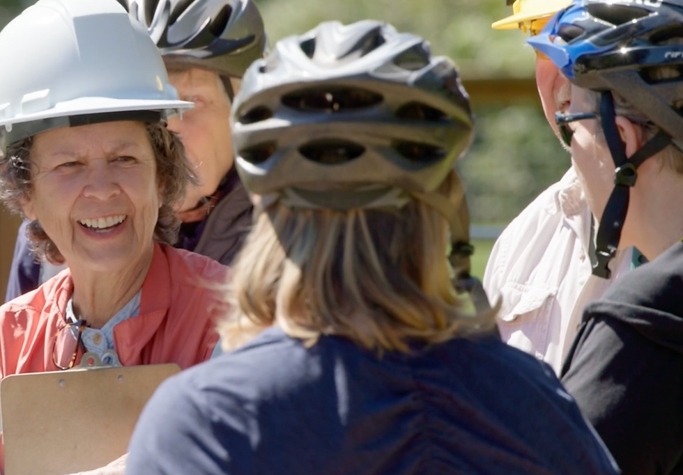 women wearing bike and construction helmets talking in a group