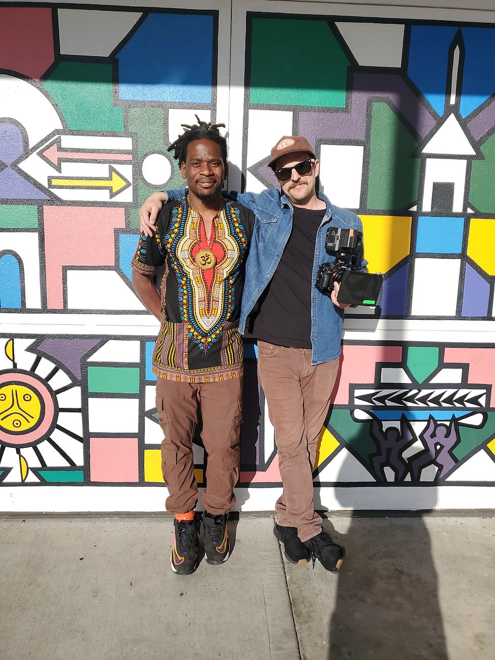 two men standing in front of a community mural at Evergreen State College