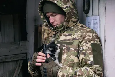 Soldier holding a black and white kitten