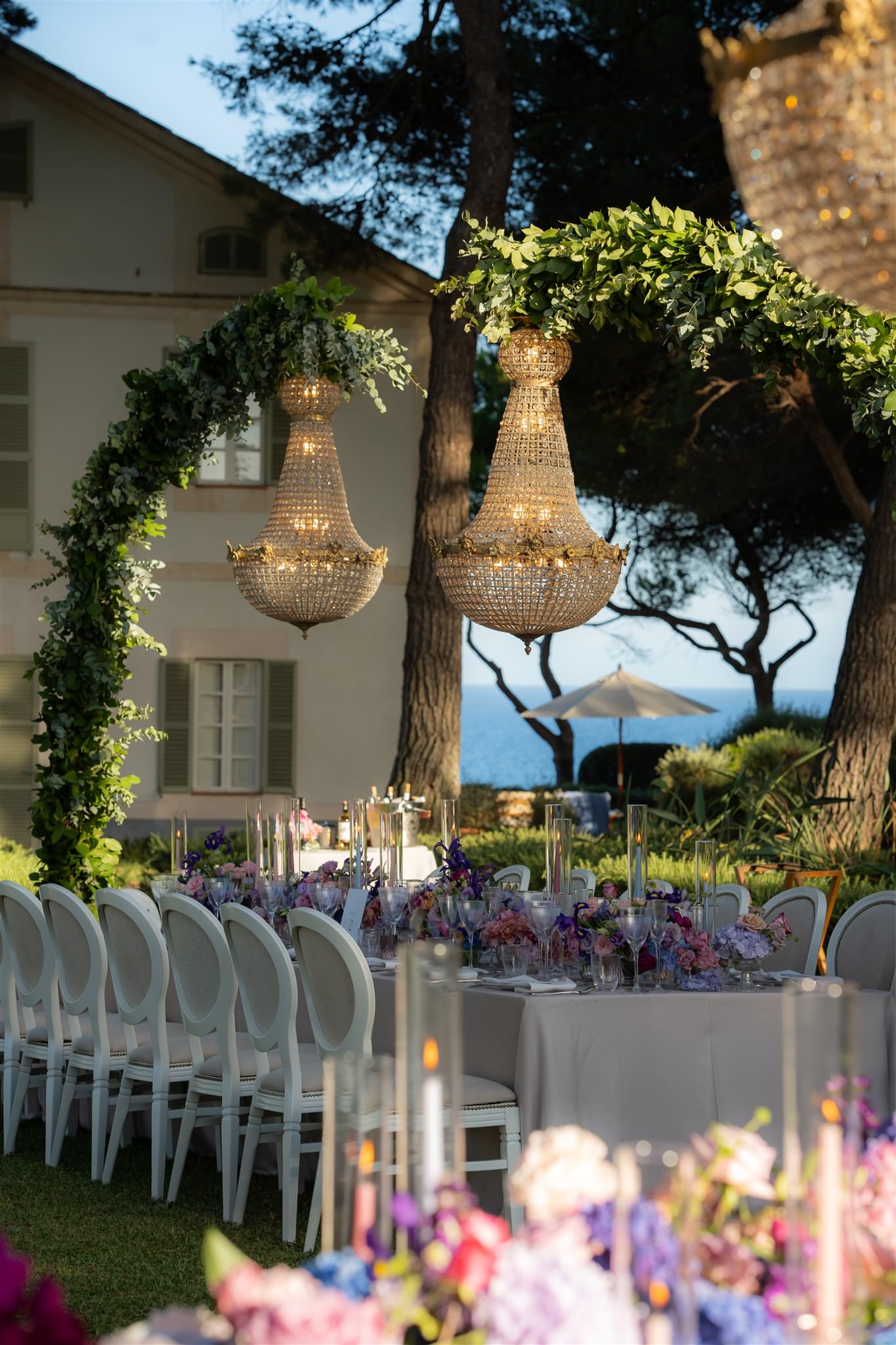 Outdoor wedding dinner setup under trees with hanging lights and long tables in th Mediterranean garden of Finca hotel Can Simoneta
