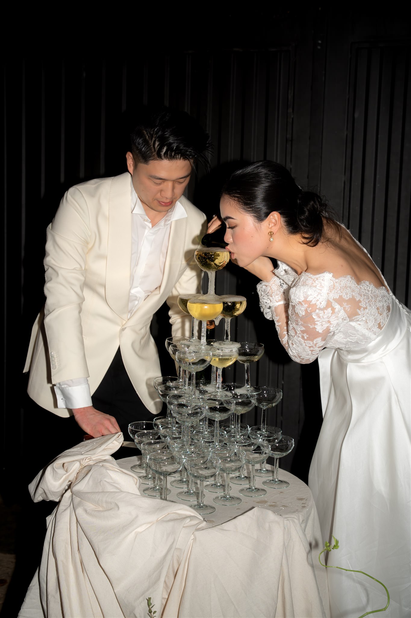 Bride and groom pouring champagne into a glass tower during wedding celebration in Bodega Terra Ion