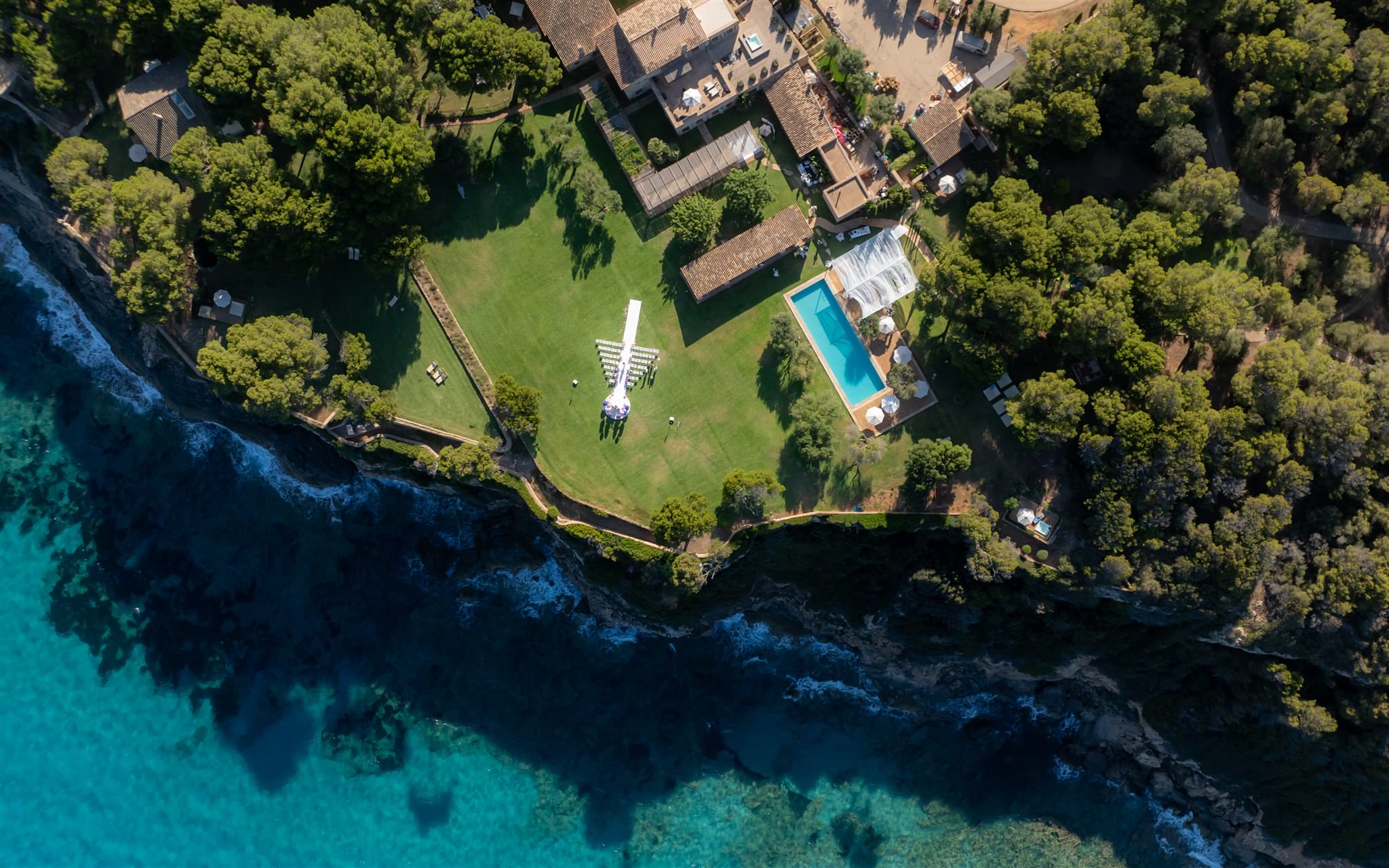 Aerial view of a luxury villa wedding venue located directly by the sea with pool and greenery in Mallorca, Spain