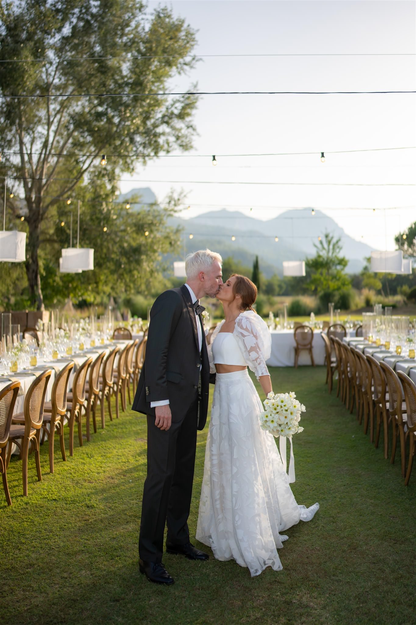 Bride and groom standing together outdoors in Almond Valley during sunset with mountains of Mallorca in the background