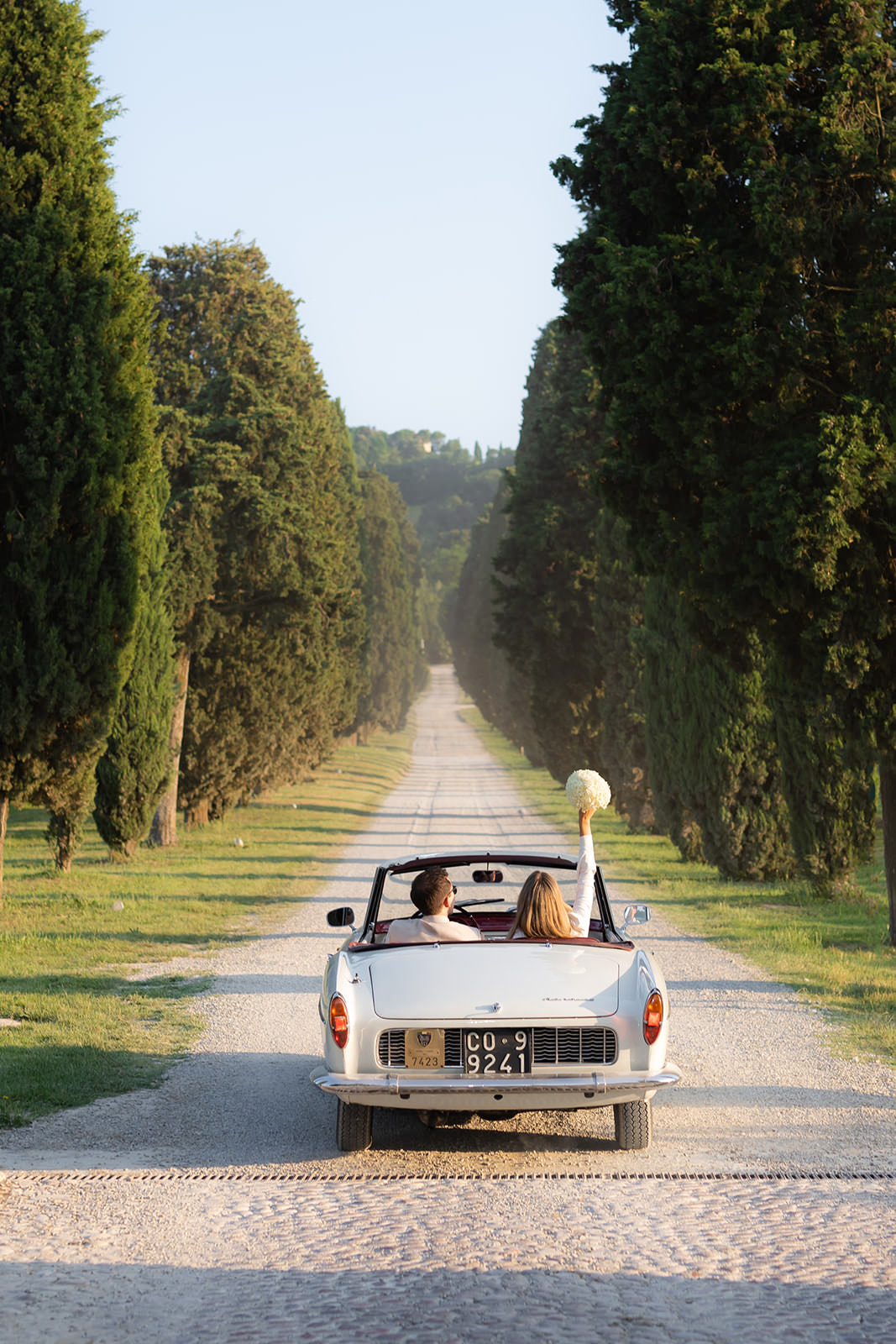 Classic car driving along a tree-lined road - classic for Tuscany - at Roncolo1888
