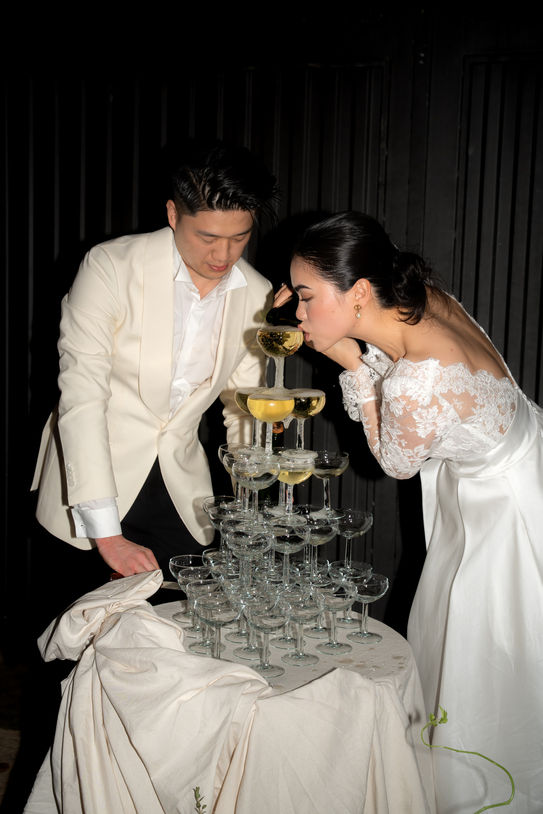 Bride and groom beside champagne tower during Mallorca wedding reception.