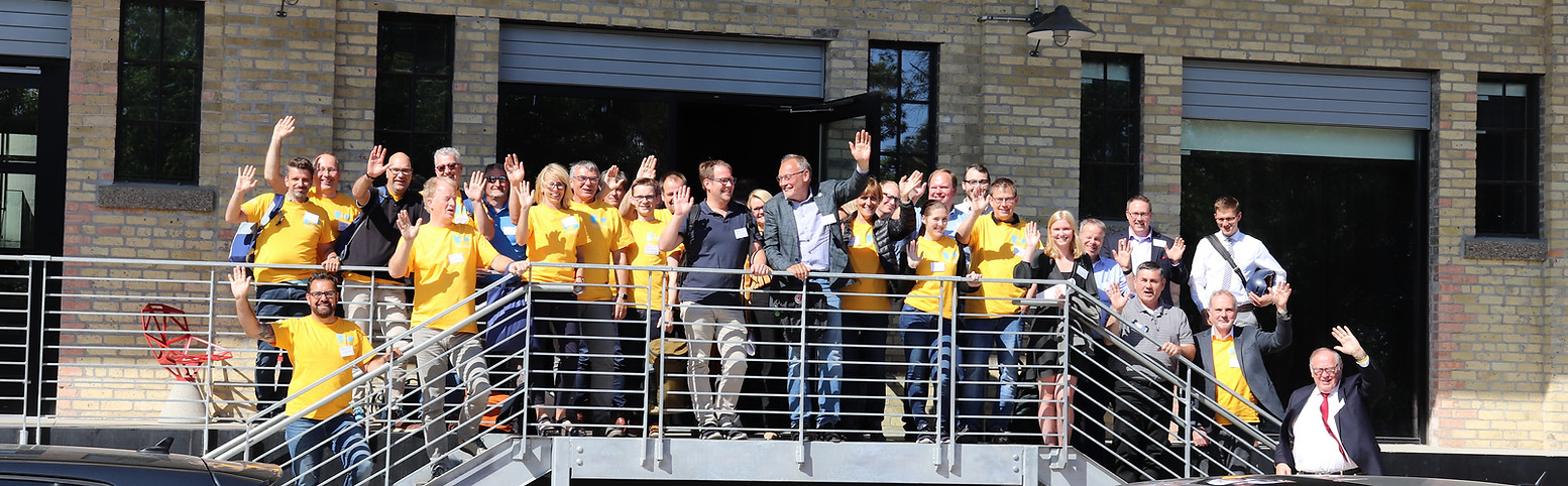 A large group of Climate Smart Municipalities participants standing on a balcony smiling and waving. 