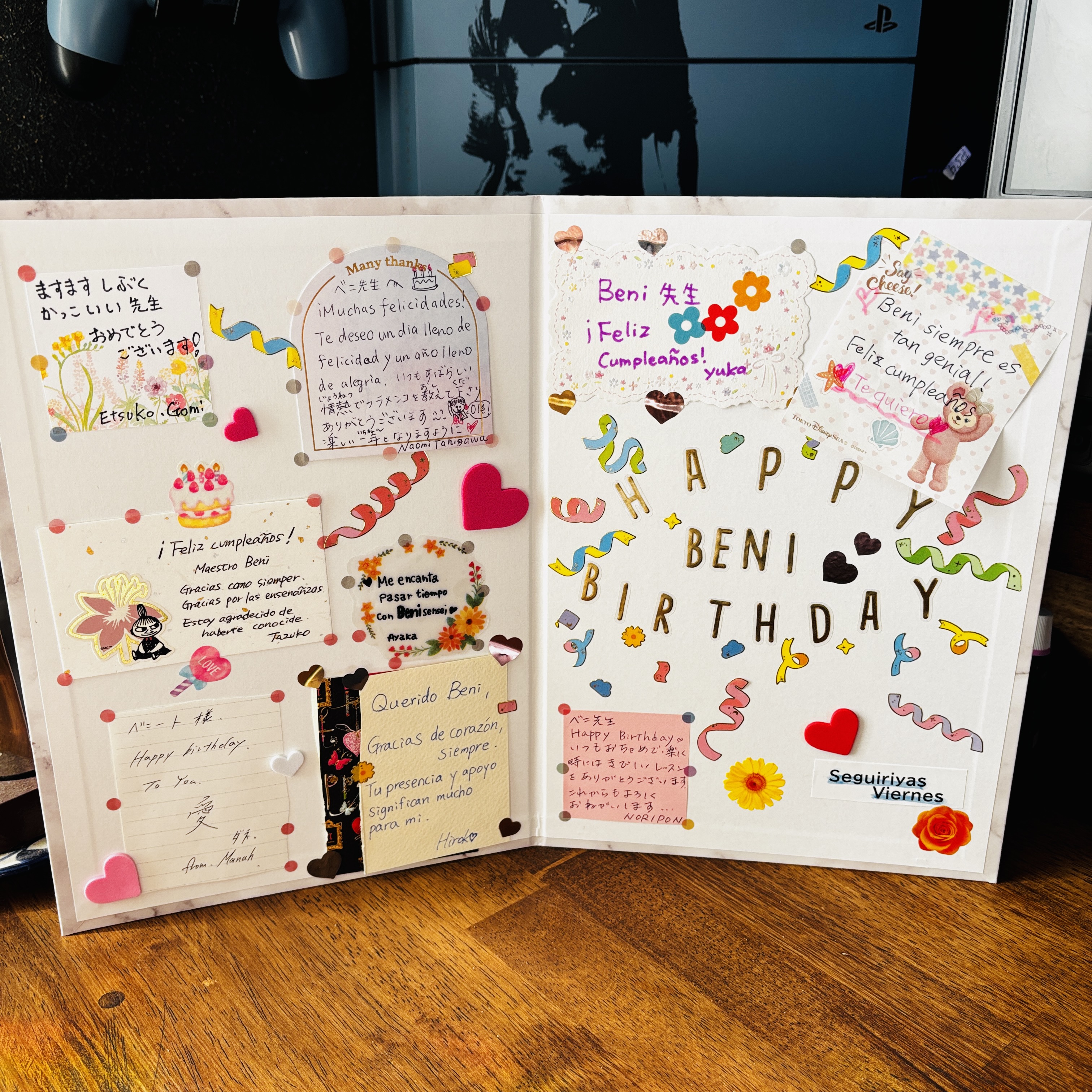 An open birthday message book decorated with colourful cards and ornaments.