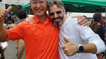 Two people pose with their arms around each other beneath event tents.