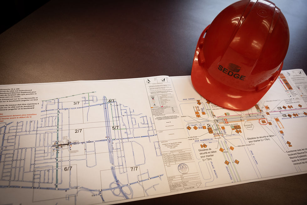 Traffic management plan and roadwork engineering drawings displayed on a desk beside a Sedge safety helmet. The image highlights traffic control planning, work zone design, and municipal compliance preparation for construction projects and road closures in Montreal and Laval.